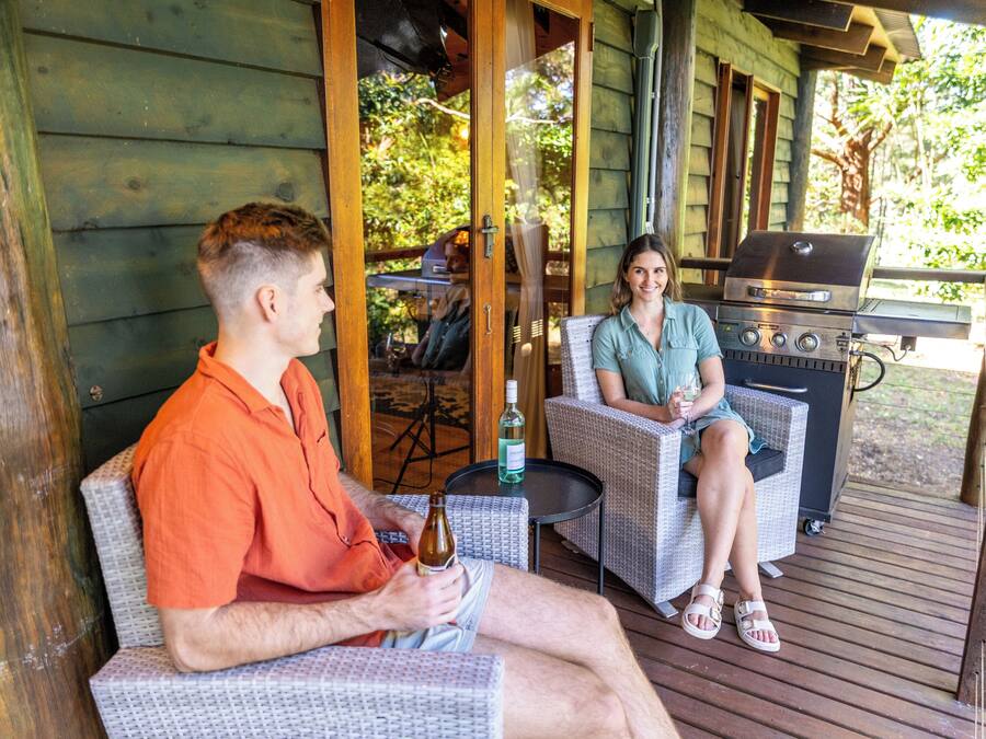 Un espace extérieur abrité, aménagé avec des chaises en osier et un barbecue.