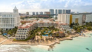 Un hotel frente al mar con varias construcciones, una playa y una piscina.