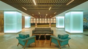 A modern lobby with a central seating area, wooden slatted ceiling, and illuminated glass partitions. - Acapulco | Beachside Weekend Stay | Pool + Beach (Acapulco)