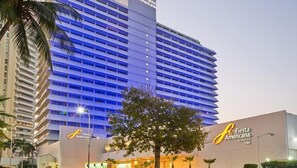 Ein Hochhaus-Hotel mit mehreren Etagen, einem gut sichtbaren 'Fiesta Americana'-Schild und einem Baum im Vordergrund.
