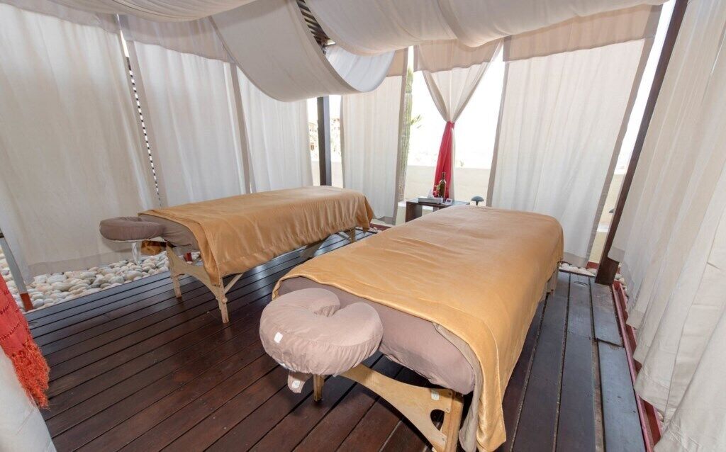 Une chambre avec deux lits, un plancher en bois et une vue sur la plage.