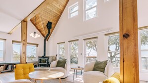 A spacious living room with a high ceiling, large windows, a fireplace, and a cozy seating area. - Escape to Tranquility: Views & Modern Amenities (Idyllwild-Pine Cove)