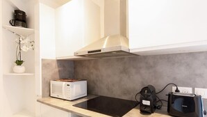 Una cocina compacta con microondas, tostadora y cafetera sobre la encimera.