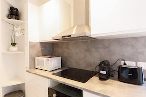 Eine kleine Küche mit einer Mikrowelle, einem Toaster und einer Kaffeemaschine auf der Arbeitsfläche.