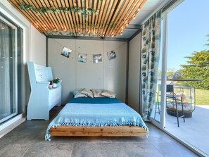 Ein Schlafzimmer mit einem hölzernen Bett, einem Schreibtisch und Blick ins Freie.