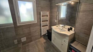 Ein modernes Badezimmer mit großem Spiegel, Waschbecken und Handtuchhalter.