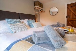 A neatly made bed with multiple pillows and a stack of towels.
