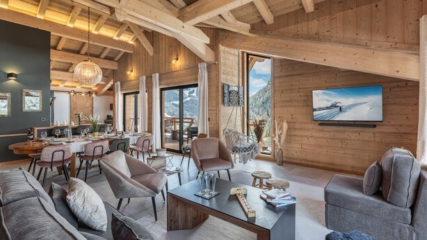 A spacious living area with a high ceiling, wooden beams, a dining area, and a large window offering a mountain view. - L'ATTIQUE - brand new apartment for 10 people in the center of Chatel (CHATEL)
