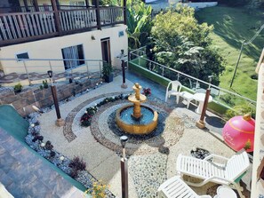 Une cour intérieure avec une fontaine centrale, entourée d’espaces aménagés pour s’asseoir et d’un bâtiment doté de balcons.