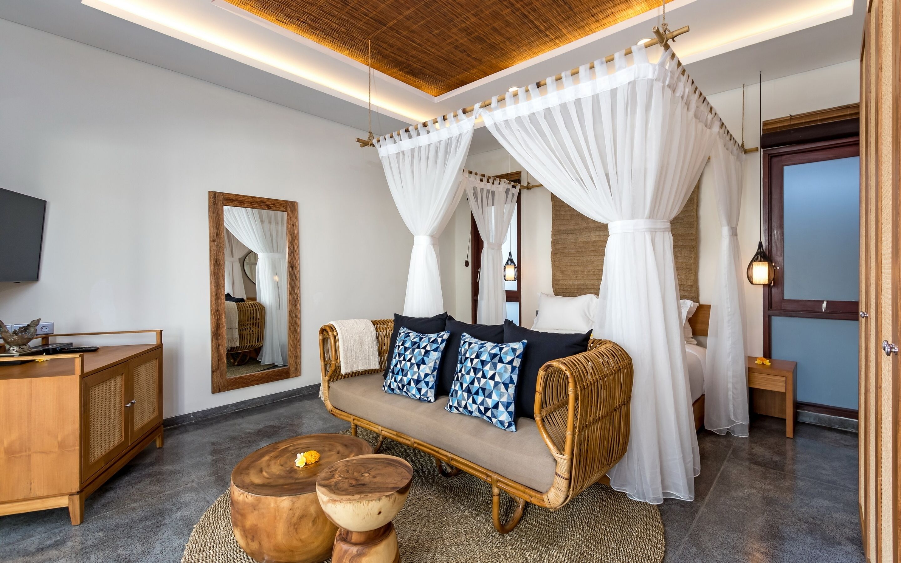 A modern bedroom with a canopy bed, a wooden cabinet, and a television.