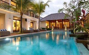 A pool area with lounge chairs and a building with a tiled roof.