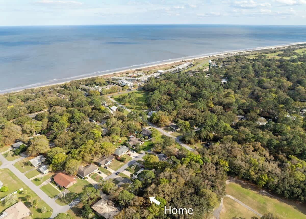 Ett flygbildsbild av ett bostadsområde med hus, vägar och en strand.