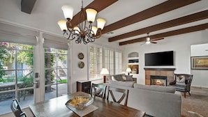 A spacious living room with a fireplace, a dining area with a wooden table, and a large window with blinds.