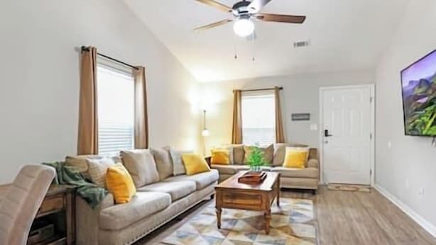 A living room with a sofa, a coffee table, and a ceiling fan.