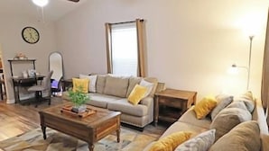 A living room with a sofa, a coffee table, a lamp, and a clock on the wall.