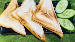 Triangular sandwiches on a black plate, a glass of milk, and sliced cucumbers. - RAON Central Hotel (Xuan Huong - Da Lat)