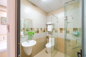 A bathroom with a glass shower enclosure, a sink, and a toilet. - RAON Central Hotel (Xuan Huong - Da Lat)