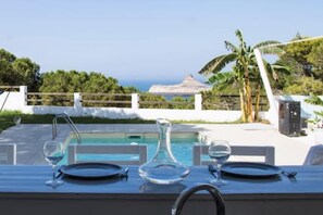 A dining table set for two with a view of a pool and palm trees. - L Appel de la for t Demeure de Charme Avec vue (Raf Raf)
