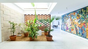 Ein modernes Interieur mit geometrischem Wanddesign, einem farbenfrohen Wandgemälde und Topfpflanzen.