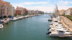 A marina with numerous boats docked along a narrow waterway, flanked by multi-story buildings with balconies. - Primavera by Interhome (Cap d'Agde)