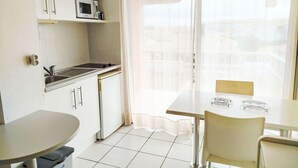A compact kitchen with a microwave, sink, and a dining area with a table and chairs. - Primavera by Interhome (Cap d'Agde)