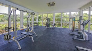 A gym with various exercise equipment, large windows, and a view of greenery outside. - Galle Holiday Home Rental - 3BR, Fast Internet, Pool, Gym, Tennis, Beach House  (Galle)