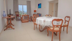A dining area with a round table covered in a white tablecloth, surrounded by wooden chairs with cushioned seats. - Galle Holiday Home Rental - 3BR, Fast Internet, Pool, Gym, Tennis, Beach House  (Galle)