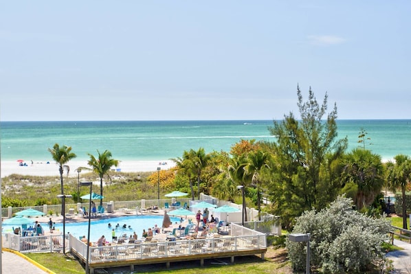 A pool area with a view of the beach and ocean.