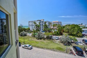 A view of a multi-story hotel with balconies, surrounded by lush greenery and parked cars.