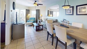 A spacious living area with a dining table, chairs, a sofa, and a ceiling fan.