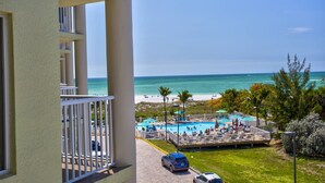 A balcony with a view of a beach and a swimming pool.
