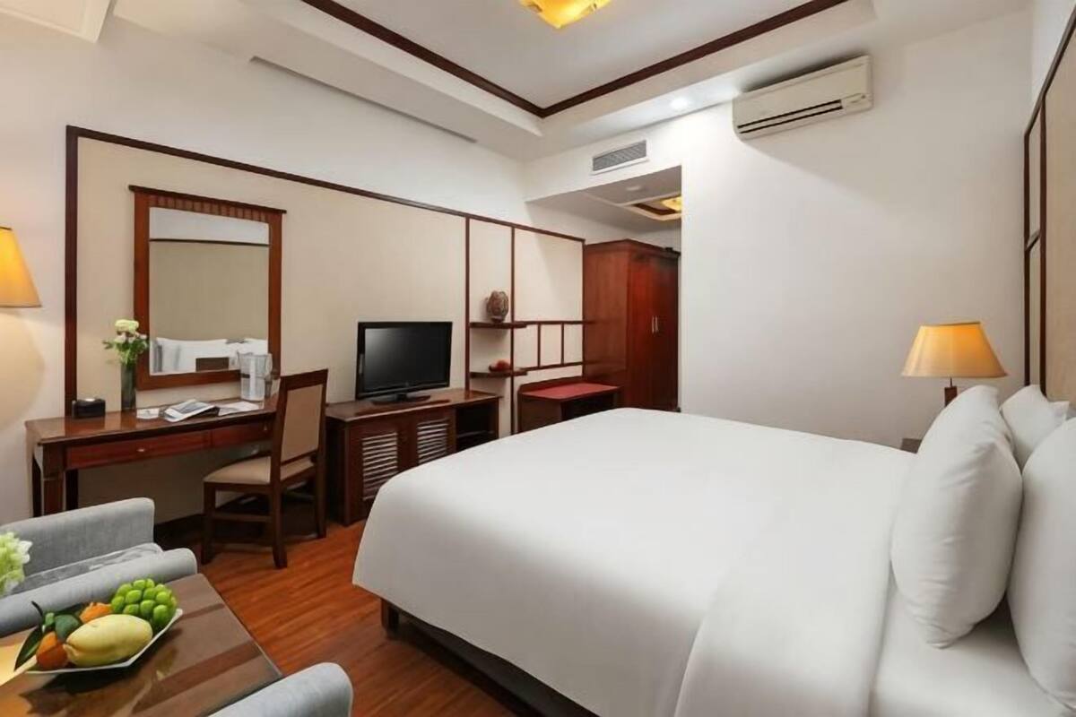 Ein Hotelzimmer mit Bett, Schreibtisch, Fernseher und einem Sessel.