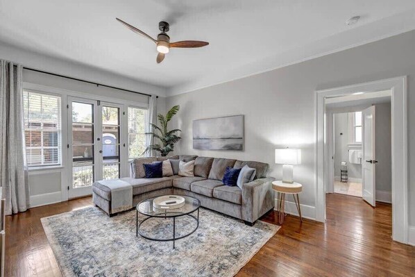 A living room with a sectional sofa, a coffee table, and a ceiling fan.