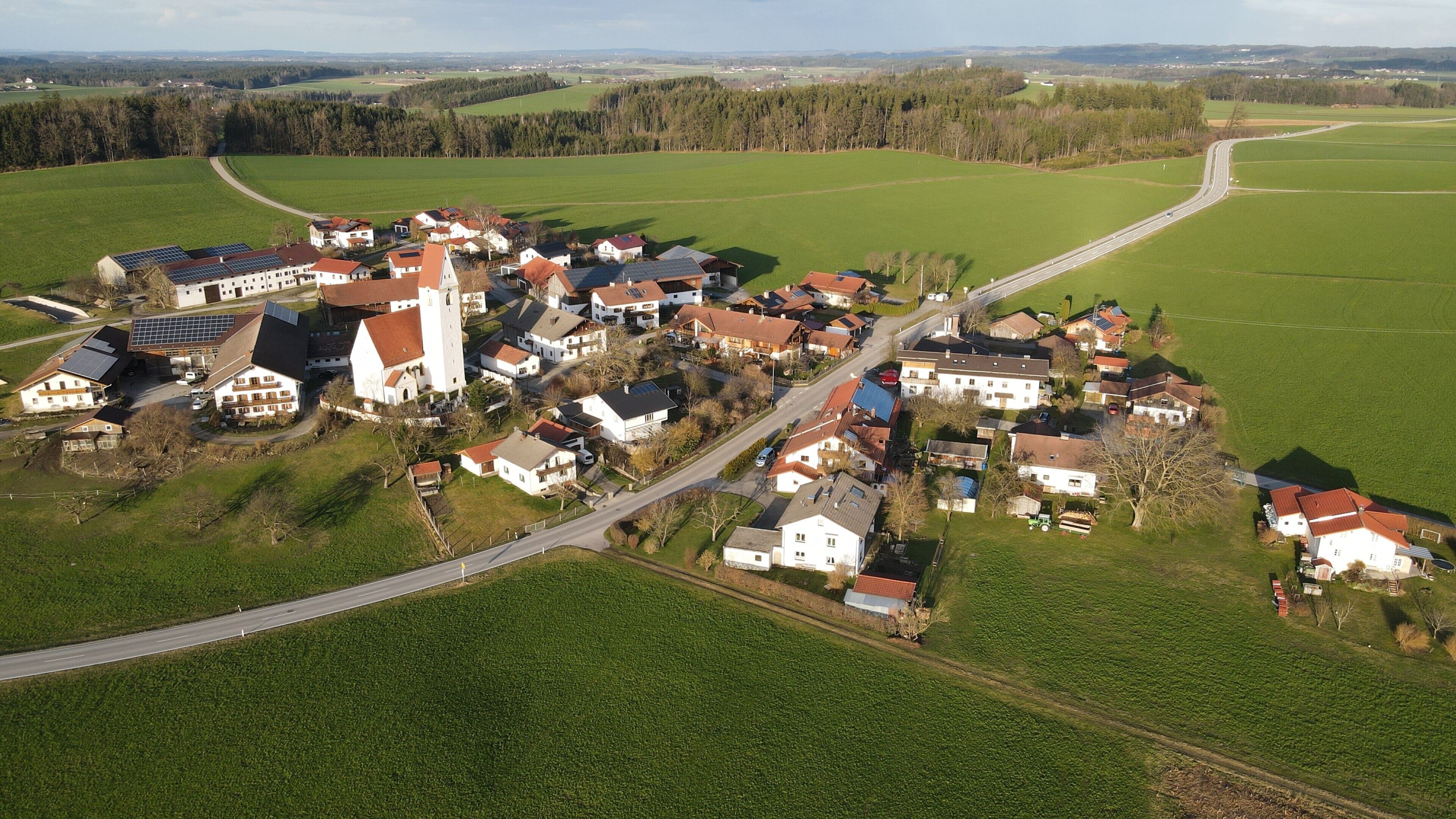Vista aérea de un pueblo rural con casas, una iglesia y campos circundantes.
