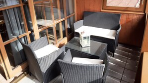 Ein Zimmer mit Rattanmöbeln, einem Glastisch und Blick durch ein Fenster.