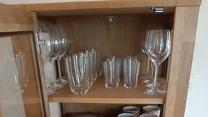 Ein Holzkabinent mit Glastüren, gefüllt mit gestapelten Tellern, verzierten Tassen und klaren Gläsern.