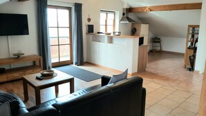 Ein zeitgemäßer Wohnbereich mit Sofa, Esstisch, Küchenzeile und Fernseher.
