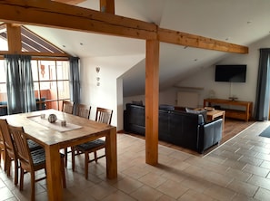 Un coin repas avec une table et des chaises en bois, un canapé et un téléviseur dans le salon.