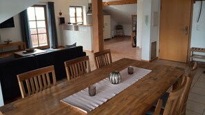 Ein Essbereich mit Holztisch, Stühlen und Blick auf Küche und Wohnraum.