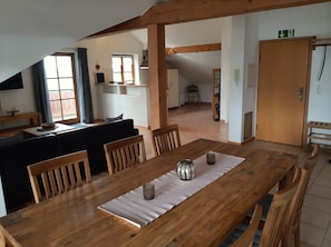 Ein Essbereich mit Holztisch, Stühlen und Blick auf Küche und Wohnraum.