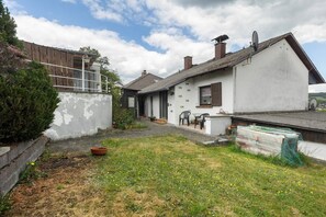 Il s’agit d’une propriété résidentielle dotée d’un jardin, d’une maison blanche avec un toit en pente et d’une antenne parabolique.