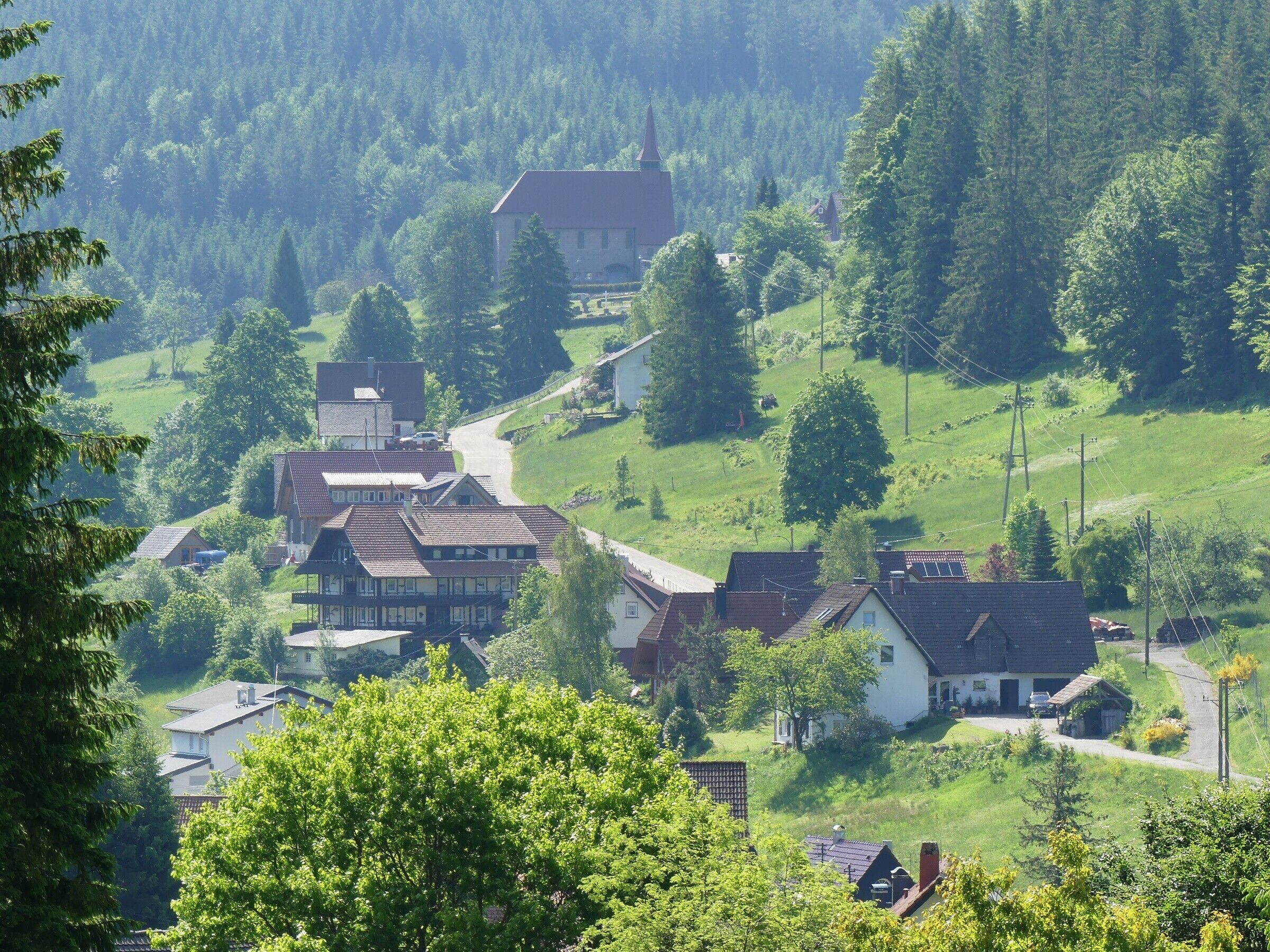 A rural village with traditional houses, a church, and a winding road.