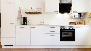 Una cocina moderna con armarios blancos, una estufa negra, un microondas y una cafetera.