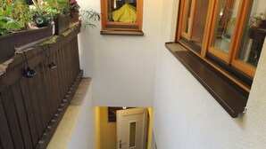 A staircase with a handrail, a door at the bottom, and a window on the right.