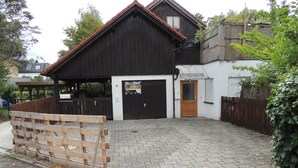 A two-story building with a dark wooden facade, a tiled roof, and a paved driveway.