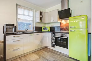 A kitchen with white cabinets, a green refrigerator, a microwave, and an oven. - Holiday Home 'Haus Segelboot Hirtenweg 3c' with Private Terrace, Private Garden and Wi-Fi (Zingst)