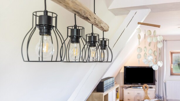 A modern interior with a sloped ceiling, exposed wooden beams, and a wall-mounted TV.