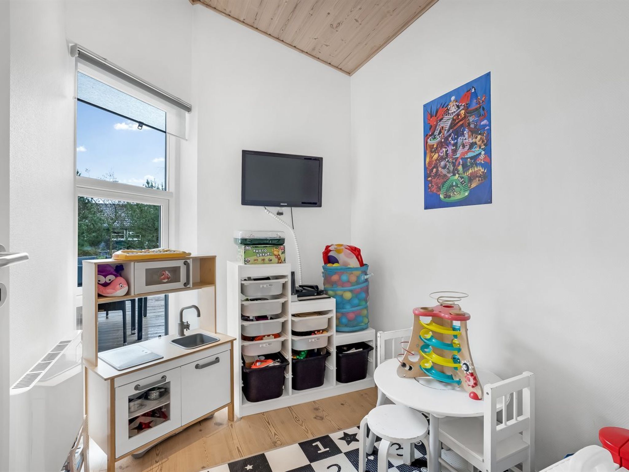 Un cuarto de juegos infantil con televisión, almacenaje y una ventana.