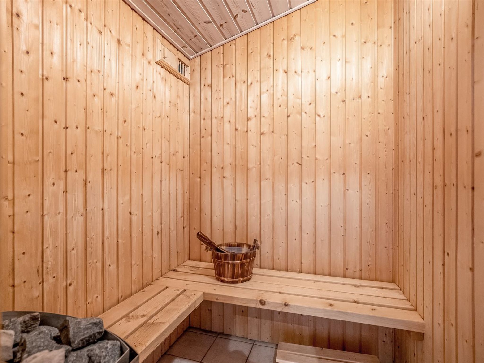 Un sauna en bois, avec des bancs et un seau pour l'eau.