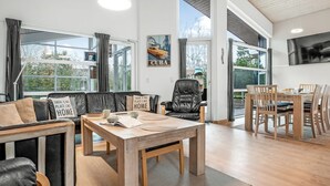 En moderne stue med sofa, spisebord og et køkkenområde.